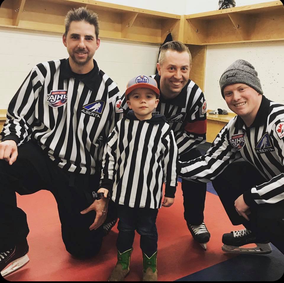 Brad Holfeld, Danny Gadowski, and Brent Young meet a young fan at an AJHL game